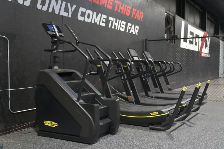 Treadmills and conditioning equipment under the painted wall text.