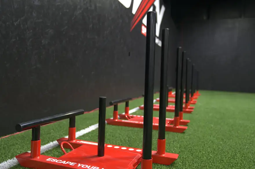 A row of red training sleds lined up on the turf.